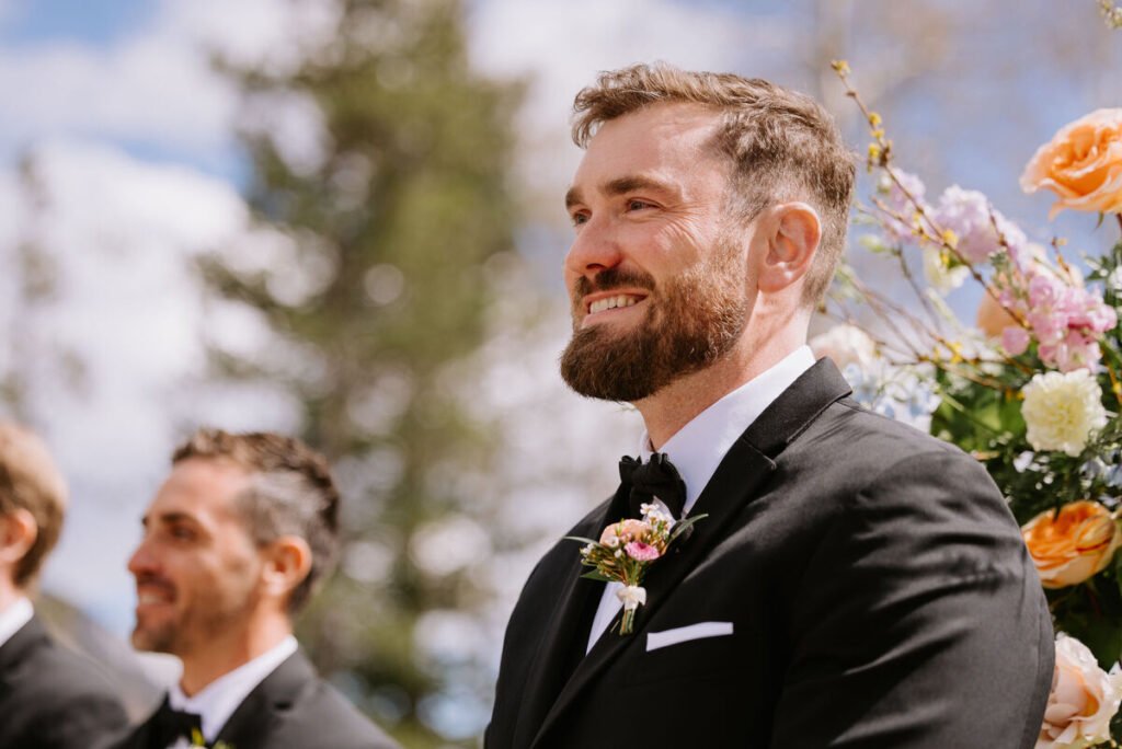 Groom wearing a floral boutonniere during an outdoor wedding ceremony at Silvertip Resort in Canmore, Alberta